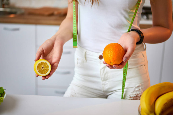Молода щаслива жінка з апельсином і лимоном (цитрусові) на сучасній кухні. Концепція здорової їжі та дієти. Розпушування ваги
 - Фото, зображення