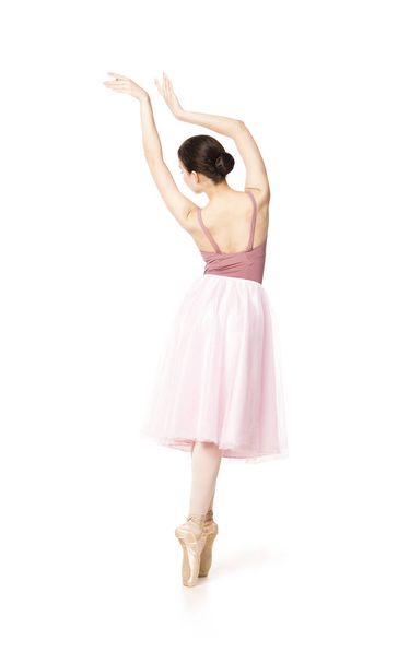 Elegant girl in a pink skirt and beige top dancing ballet. - 写真・画像