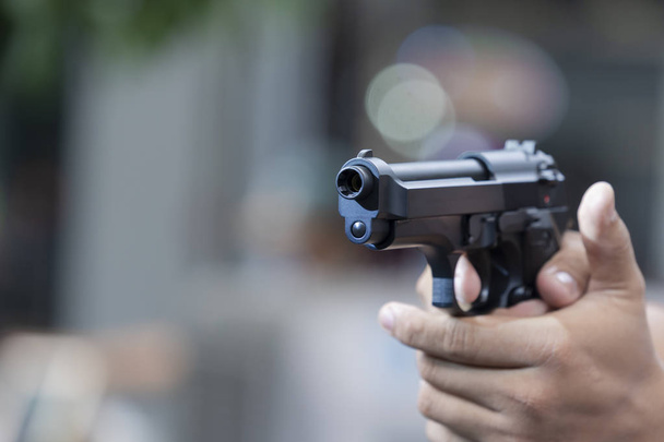 Man holding gun aiming pistol in hand ready to shoot - Valokuva, kuva