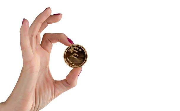 Mão feminina segurando uma moeda de ouro com a inscrição OURO 9999
. - Foto, Imagem