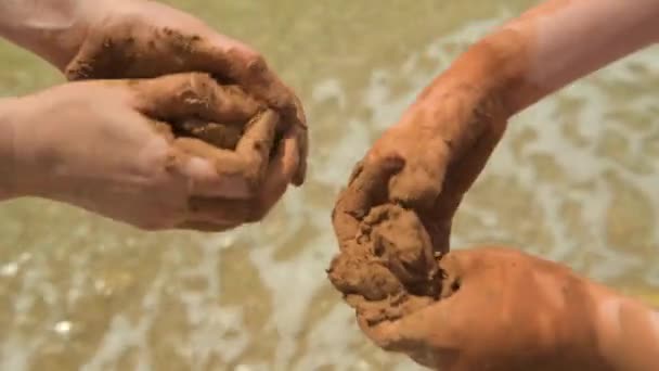 Nahaufnahme von Händen, die Lehm am Meeresstrand machen, Sand und Welle als Hintergrund, Sommer- und Reisekonzept. - Filmmaterial, Video
