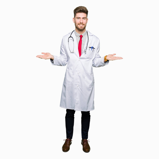 Молодий красивий лікар чоловік в медичному пальто Усміхнений показує обидві руки відкриті долоні, представляючи порівняння і рекламний баланс
 - Фото, зображення