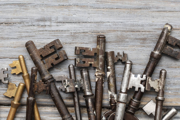 Vintage old fashioned keys on a rustic wooden background. Security concept - 写真・画像
