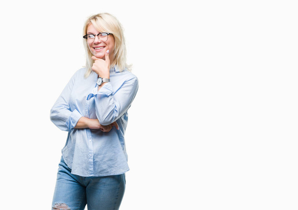 Young beautiful blonde business woman wearing glasses over isolated background looking confident at the camera with smile with crossed arms and hand raised on chin. Thinking positive. - Fotografie, Obrázek