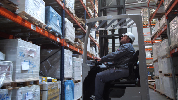 Pracovník skladu na vysokozdvižný vozík na paletě se zbožím. 4k pomalá mo - Záběry, video