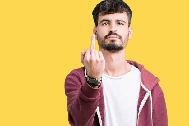 Молодой красивый мужчина на изолированном фоне показывает средний палец, невежливый и грубый отъебись выражение лица
 - Фото, изображение