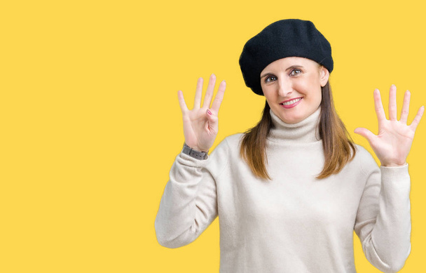 Middle age mature woman wearing winter sweater and beret over isolated background showing and pointing up with fingers number nine while smiling confident and happy. - Foto, afbeelding