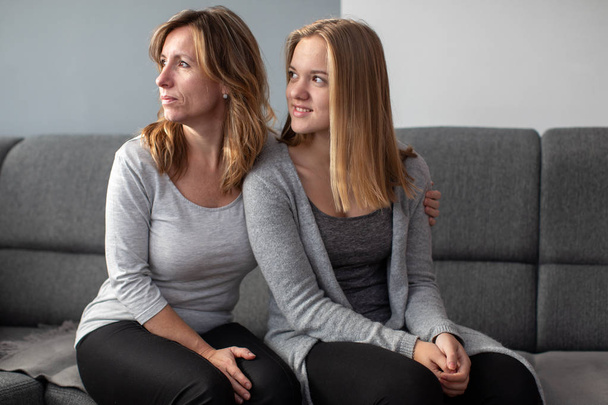 Teenage girl with her mother on a sofa in their living room - Foto, Imagen