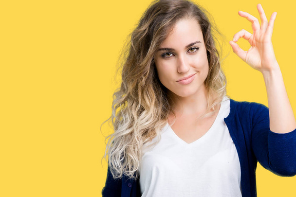 Beautiful young blonde woman over isolated background smiling positive doing ok sign with hand and fingers. Successful expression. - Photo, Image