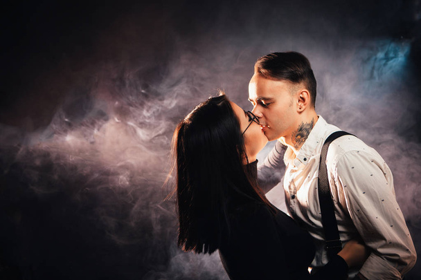 Couple in fashionable clothes on a dark smoky background - Фото, зображення