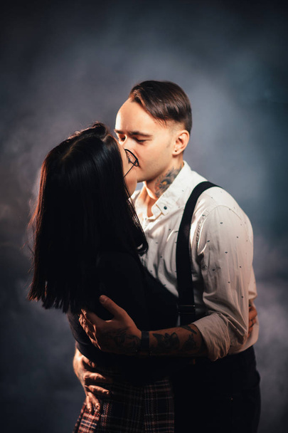 Couple in fashionable clothes on a dark smoky background - Foto, afbeelding