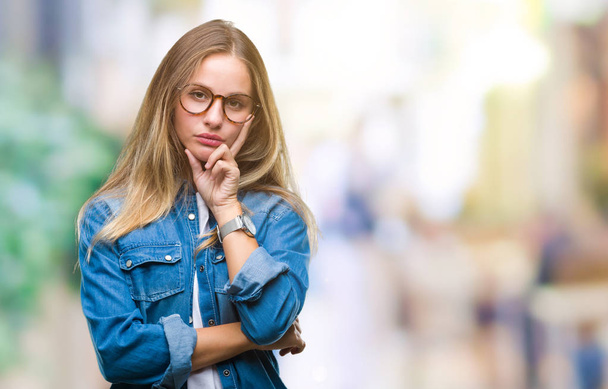 Young beautiful blonde woman wearing glasses over isolated background thinking looking tired and bored with depression problems with crossed arms. - Фото, изображение