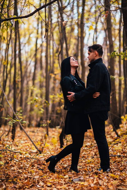 The girl and the guy are walking in the autumn forest - Фото, изображение