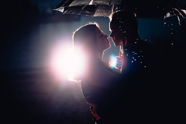 young man and woman under an umbrella and rain - Foto, afbeelding
