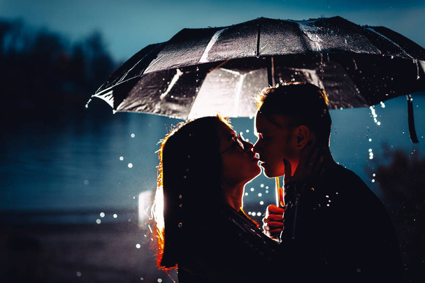 young man and woman under an umbrella and rain - Foto, immagini