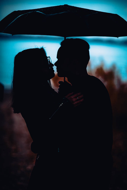 young man and woman under an umbrella and rain - Φωτογραφία, εικόνα