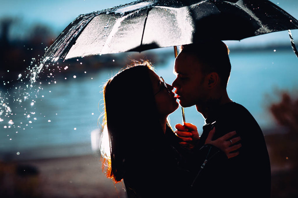 joven hombre y mujer bajo un paraguas y lluvia
 - Foto, Imagen