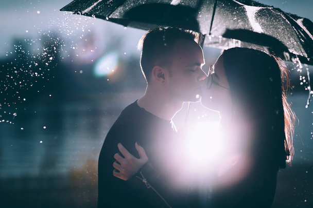 young couple standing under a dark umbrella - Foto, Imagem