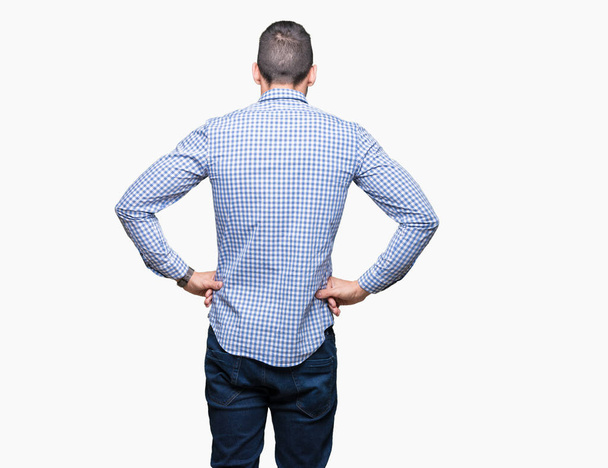 Молодой бизнесмен в очках на изолированном фоне, стоя задом наперёд, смотрит с руками на тело
 - Фото, изображение