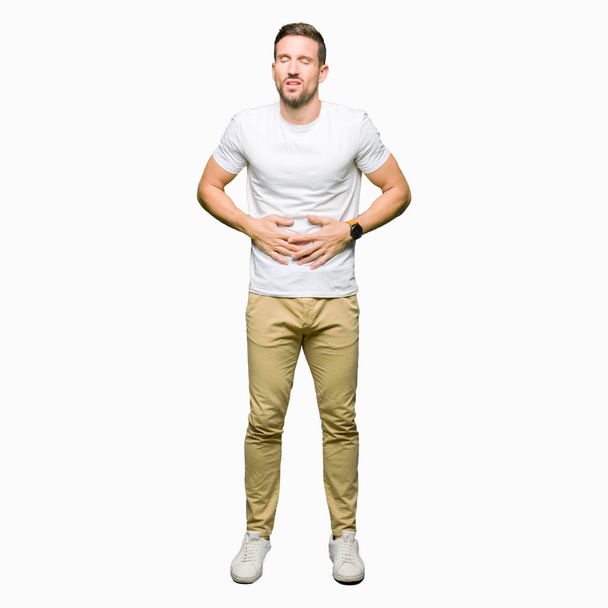 Komea mies päällään rento valkoinen t-paita käsi vatsassa, koska ruoansulatushäiriöt, kivulias sairaus huonovointisuus. Ache-käsite
. - Valokuva, kuva