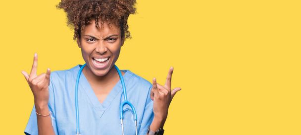 Молодий афроамериканець лікар жінка над ізольованих фон кричали з crazy вираз робити рок символ з руки. Зірка музики. Важкі концепції. - Фото, зображення