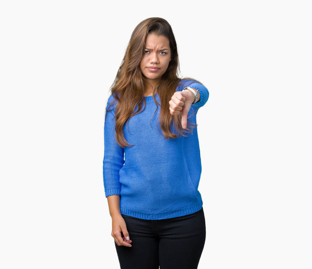若い美しいブルネット女性の不幸と怒りの拒否反応を示さずとジェスチャーを親指で否定的な分離の背景に青いセーターを着ています。不適切な表現. - 写真・画像