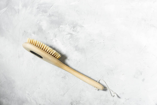 Wooden brush for dry massage lies on a gray background. View from above - Foto, Imagem