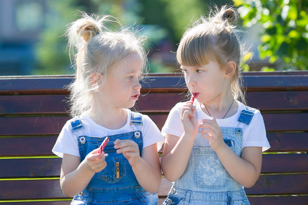 Δύο κορίτσια τρώνε γλυκά στο πάρκο. - Φωτογραφία, εικόνα