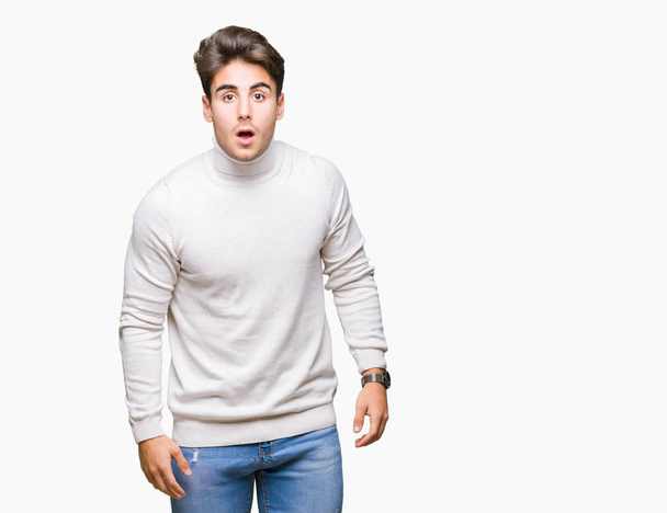 Young handsome man wearing turtleneck sweater over isolated background afraid and shocked with surprise expression, fear and excited face. - Photo, Image