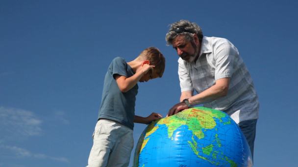 Senior con nieto de pie y estudiar la Tierra por bola inflable
 - Imágenes, Vídeo
