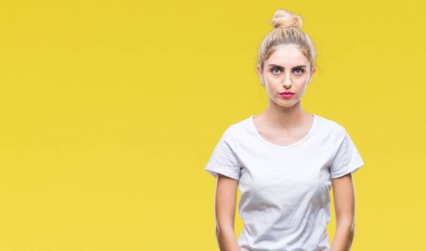 Young beautiful blonde woman wearing white t-shirt over isolated background with serious expression on face. Simple and natural looking at the camera. - Photo, image