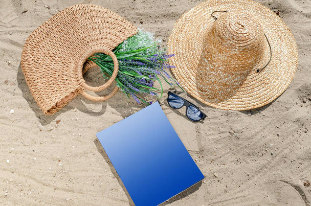 Γυαλιά ηλίου με ψάθινο καπέλο και τσάντα που βρίσκεται στην άμμο στο Μπι - Φωτογραφία, εικόνα
