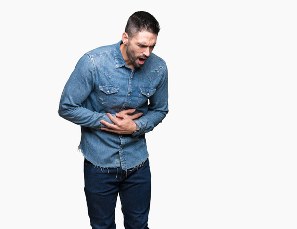 Jonge knappe man over geïsoleerd achtergrond met hand op de maag omdat indigestie, pijnlijke ziekte onwel. Ache concept. - Foto, afbeelding