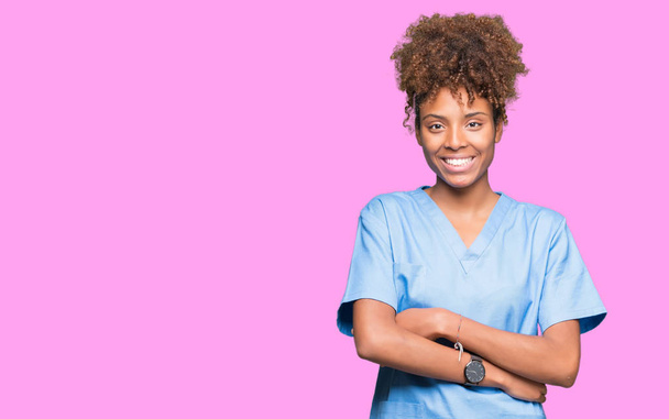 Молодая африканская американка-врач на изолированном фоне счастливое лицо улыбается со скрещенными руками, глядя в камеру. Позитивный человек
. - Фото, изображение