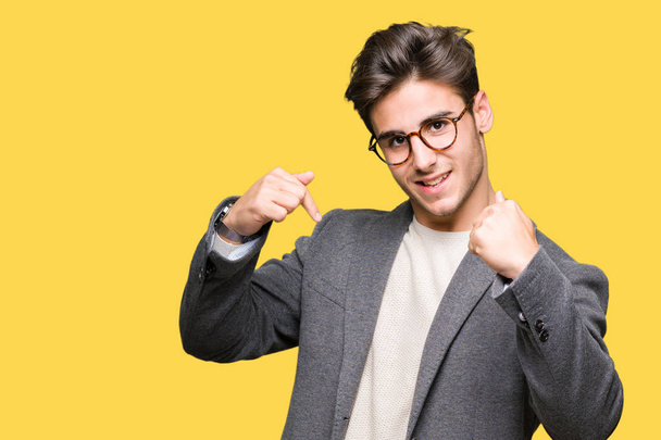 Young business man wearing glasses over isolated background looking confident with smile on face, pointing oneself with fingers proud and happy. - Photo, Image