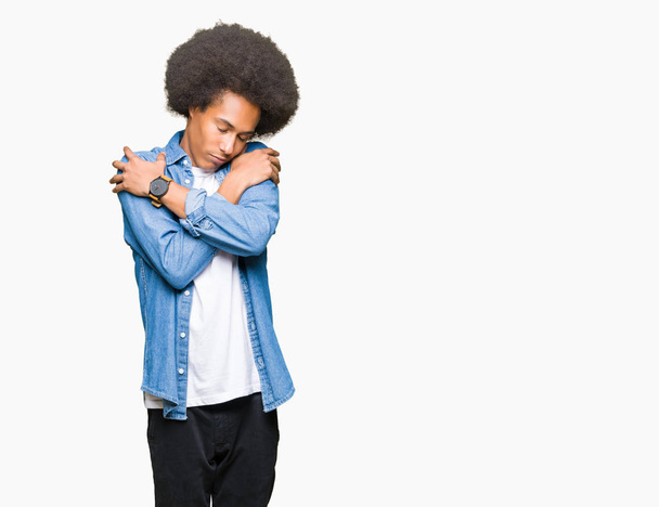 Молодой африканский американец с афроволосами, обнимающий себя счастливым и позитивным, уверенно улыбающийся. Самолюбие и забота о себе
 - Фото, изображение