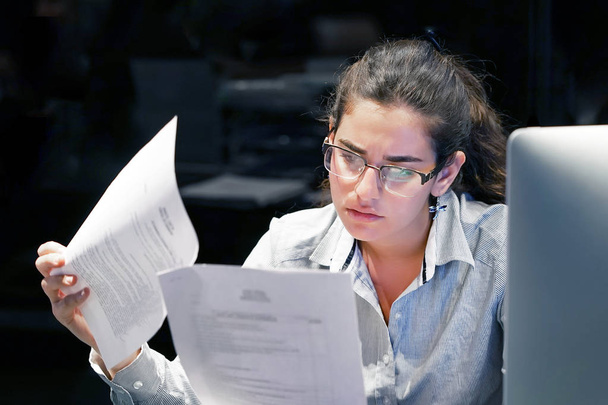 Женщина, читающая документ на рабочем месте
 - Фото, изображение