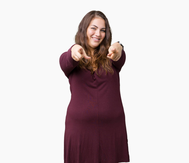 Beautiful and attractive plus size young woman wearing a dress over isolated background Pointing to you and the camera with fingers, smiling positive and cheerful - Photo, Image