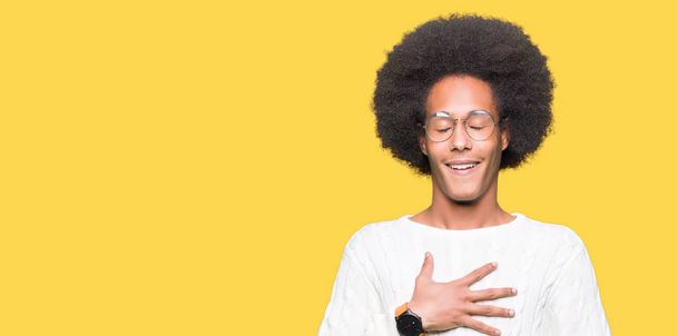 Joven afroamericano con el pelo afro usando gafas sonriendo y riendo en voz alta porque divertido chiste loco. Expresión feliz
. - Foto, imagen