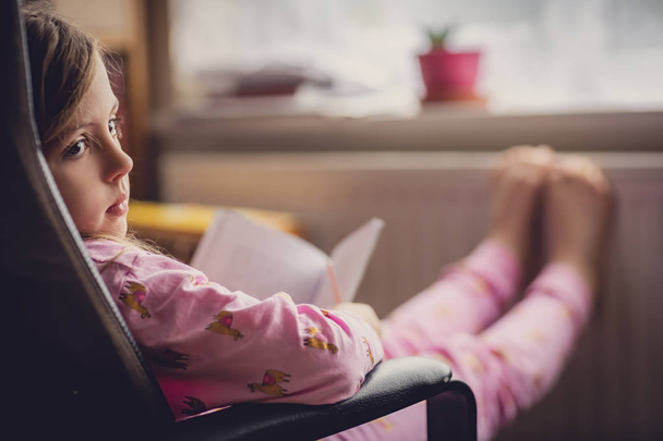 Menina no pijama lendo um livro
 - Foto, Imagem