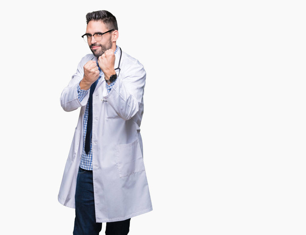 Handsome young doctor man over isolated background Ready to fight with fist defense gesture, angry and upset face, afraid of problem - Foto, Imagem