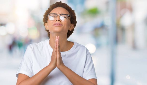 Kaunis nuori afrikkalainen amerikkalainen nainen yllään lasit yli eristetty tausta kerjääminen ja rukoilee kädet yhdessä toivon ilme kasvot hyvin emotionaalinen ja huolissaan. Pyytää anteeksiantoa. Uskonnon käsite
. - Valokuva, kuva