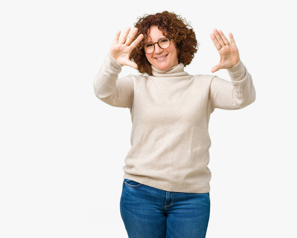 美しい中間エイガー年配の女性の身に着けているタートルネックのセーターと分離で眼鏡の背景の笑顔手のひらと指, カメラの視点を使用してフレームをやって - 写真・画像
