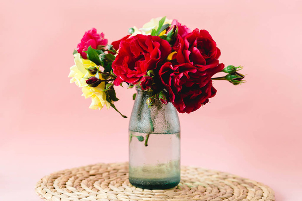 Composição impressionante de rosas coloridas em um vaso de vidro em um guardanapo de vime
 - Foto, Imagem