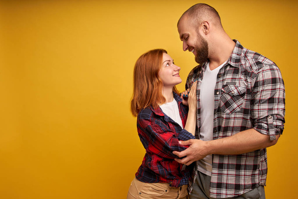 Sisäistä rakkautta. Profiilin puolella näkymä kuva komea poikaystävä tyttöystävä valmis suudella halauksia koskettaa katsomalla silmiin pukeutunut ruudullinen paita eristetty keltaisella taustalla
 - Valokuva, kuva