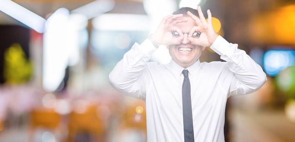 Средневековые бизнесмены в очках на изолированном фоне делают нормальный жест, как бинокль, торчащий языком, глаза смотрят сквозь пальцы. Сумасшедшее выражение
. - Фото, изображение