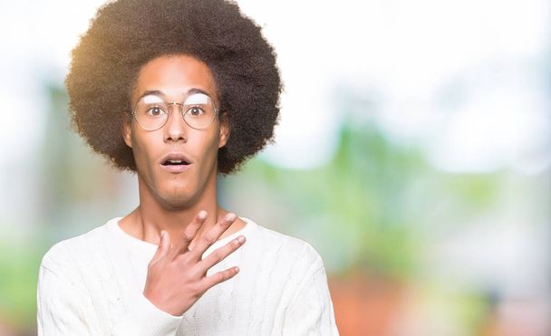 Młody African American Man z Afro włosy noszenie okulary boi i wstrząśnięty z niespodzianką wyraz, strach i podekscytowany twarz. - Zdjęcie, obraz