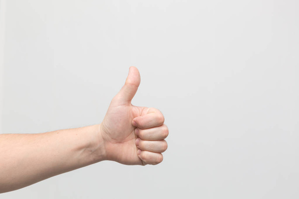 Closeup of male hand showing thumbs up sign against white background - Φωτογραφία, εικόνα