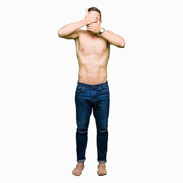 Hombre guapo sin camisa mostrando el pecho desnudo Cubriendo los ojos y la boca con las manos, sorprendido y sorprendido. Ocultar emoción
 - Foto, imagen