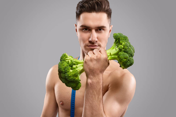 Shirtless athlete exercising with broccoli dumbbell - Fotoğraf, Görsel